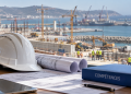 Casque, plans et dossier Compétences devant un chantier portuaire.
